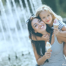 Mutter hat Kind auf dem Rücken, beide essen ein Eis