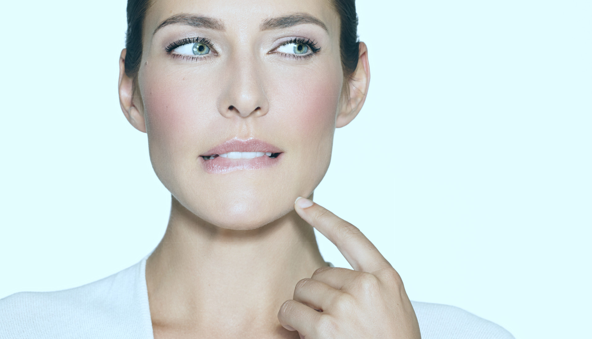 Frau beißt sich auf die Unterlippe und schaut zur Seite