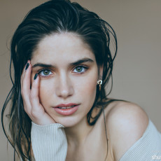 Junge Frau stützt ihr Gesicht und schaut in die Kamera